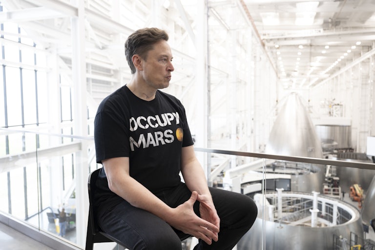 Elon Musk purses his lips while sitting in the SpaceX facility in Brownsville, Texas