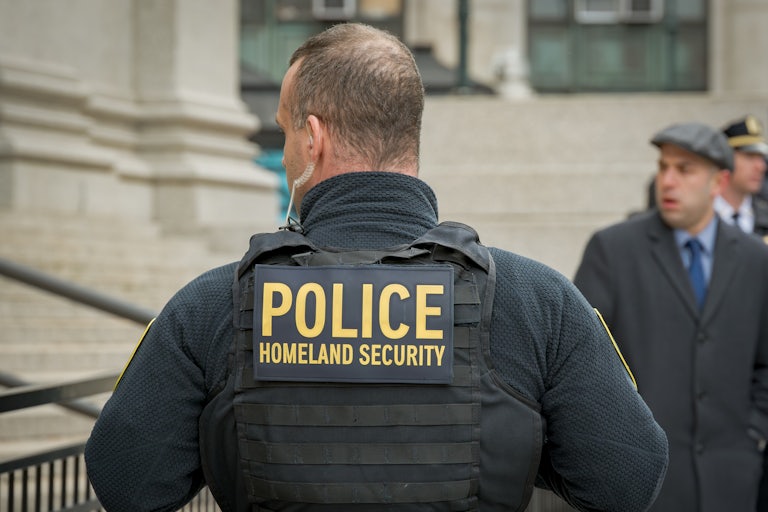 An Immigration and Customs Enforcement officer wears a tactical vest that says, "Police Homeland Security"