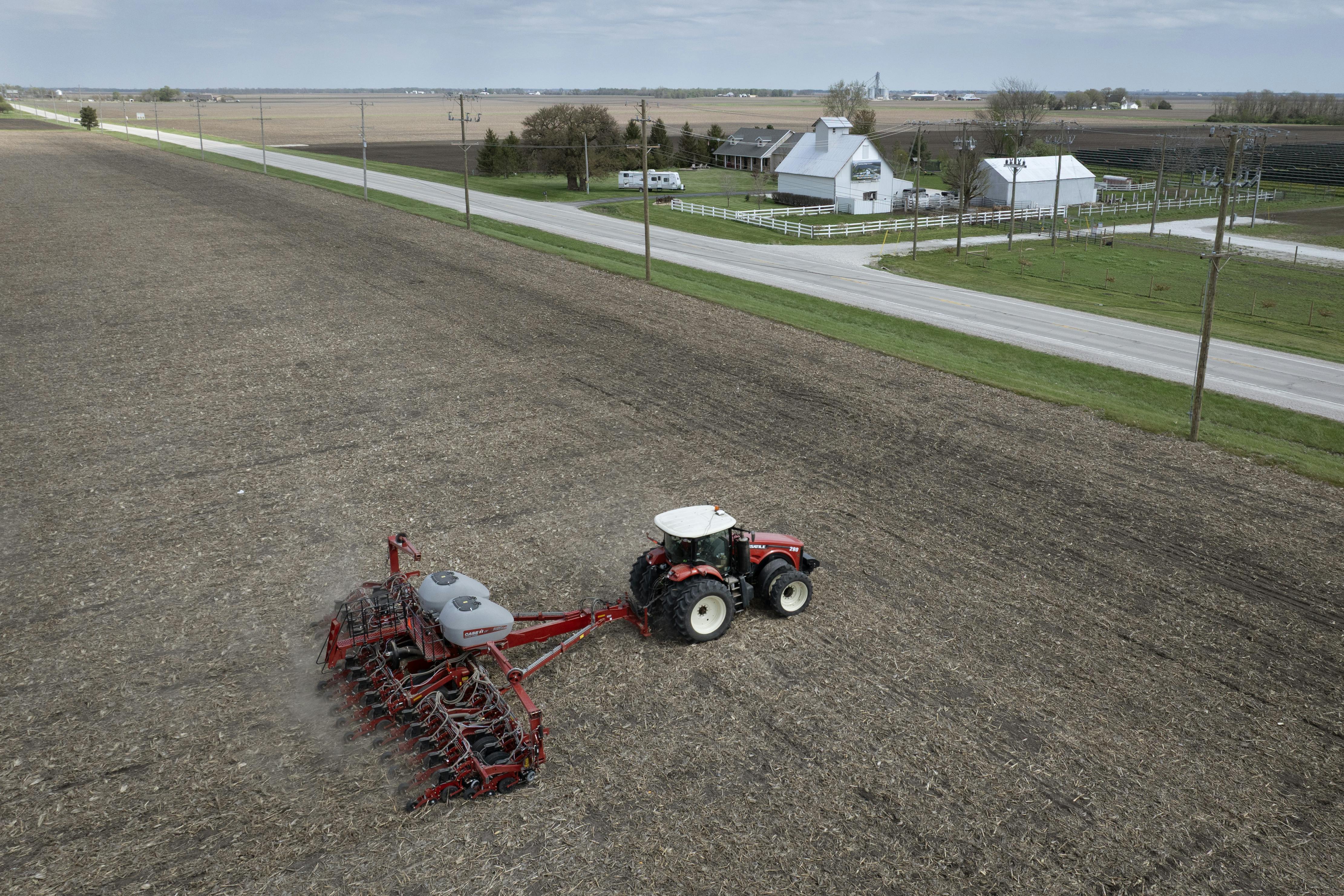 In this aerial view, a farmer uses a tractor to plant soybeans.