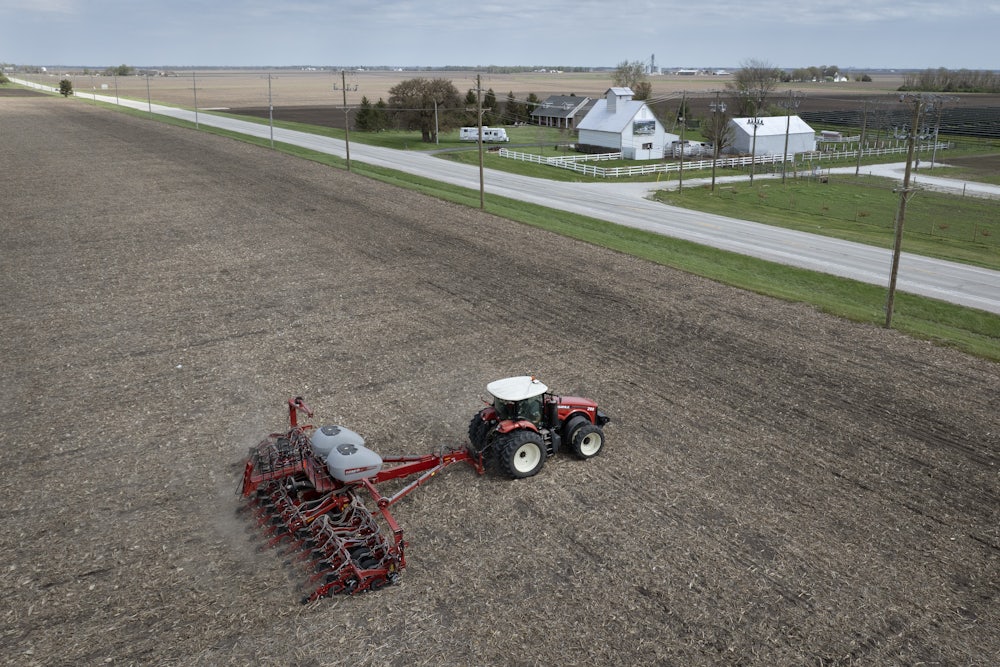 In this aerial view, a farmer uses a tractor to plant soybeans.