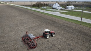In this aerial view, a farmer uses a tractor to plant soybeans.