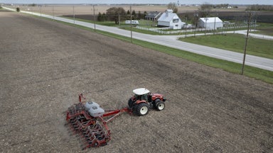 In this aerial view, a farmer uses a tractor to plant soybeans.