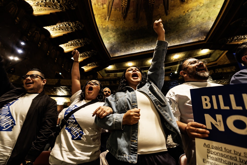 People wearing “Tax the Billionaires” shirts cheer at a Bernie Sanders–led rally in Los Angeles