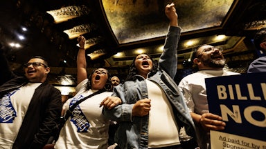 People wearing “Tax the Billionaires” shirts cheer at a Bernie Sanders–led rally in Los Angeles