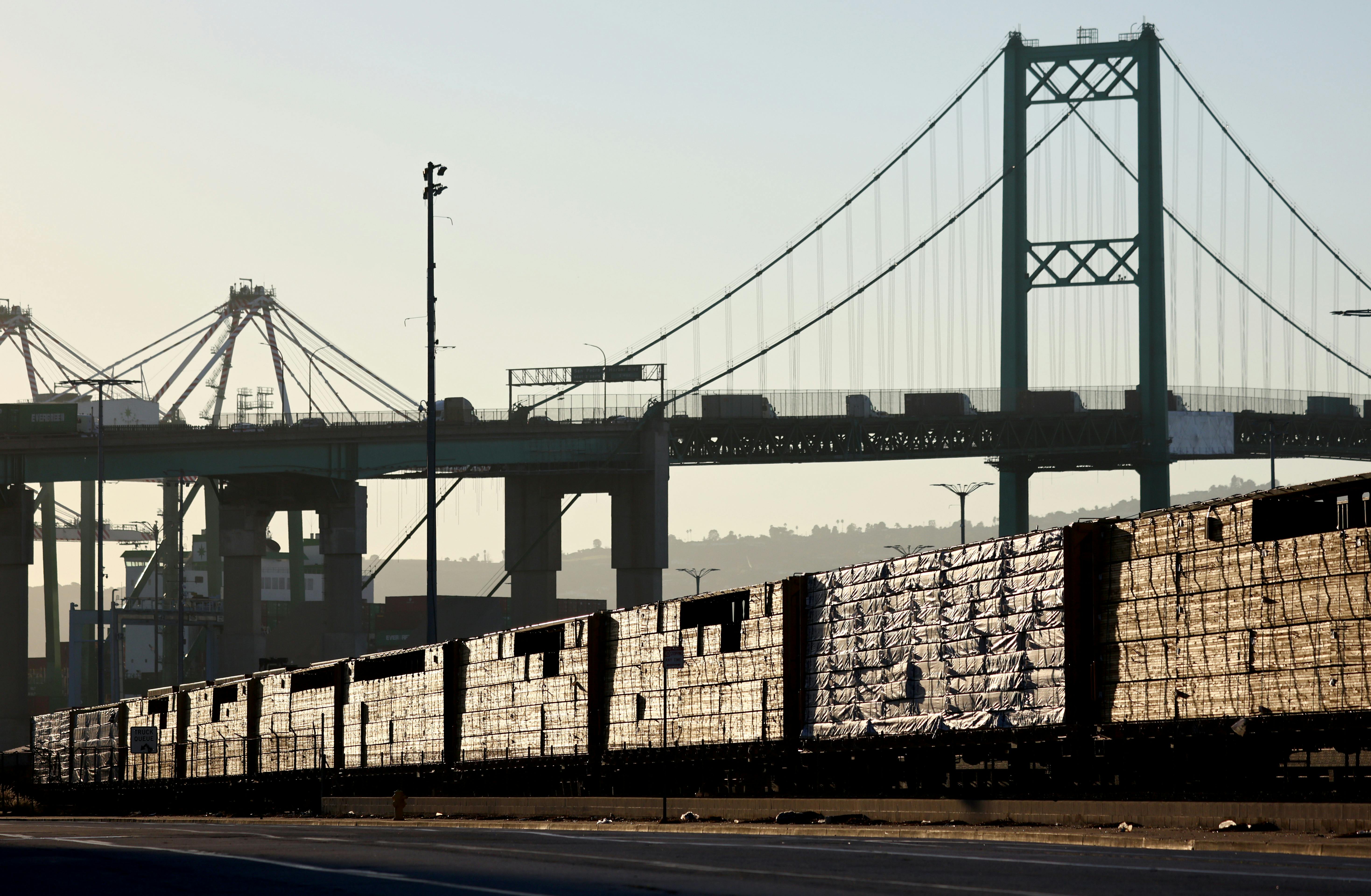 Loaded freight cars sit beneath a bridge.