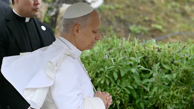Pope Leo, seen in profile, stands with his eyes close and his hands folded in front of his stomach during a visit to an archaeological site in Algeria