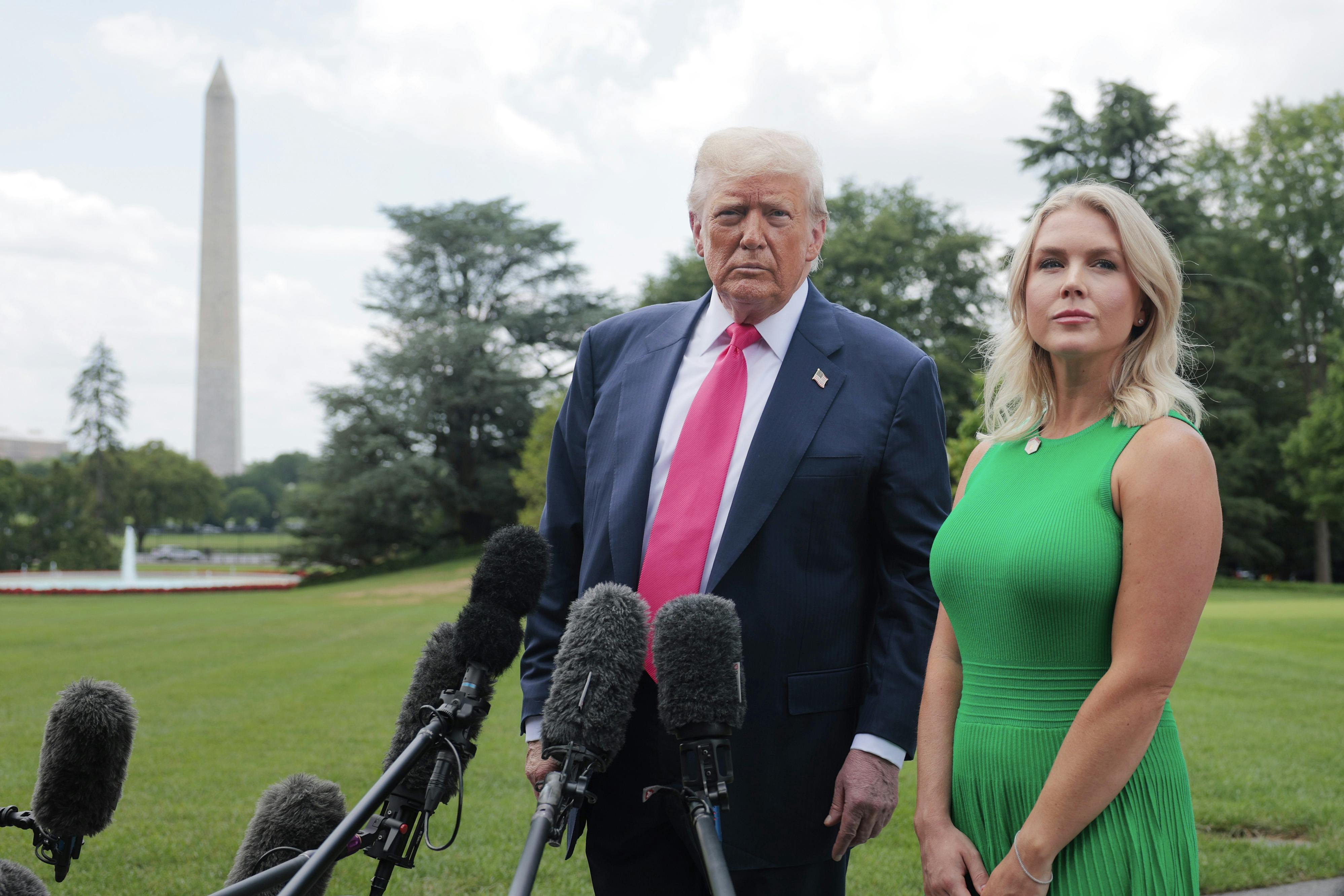 Donald Trump and Karoline Leavitt stand next to each other outside the White House
