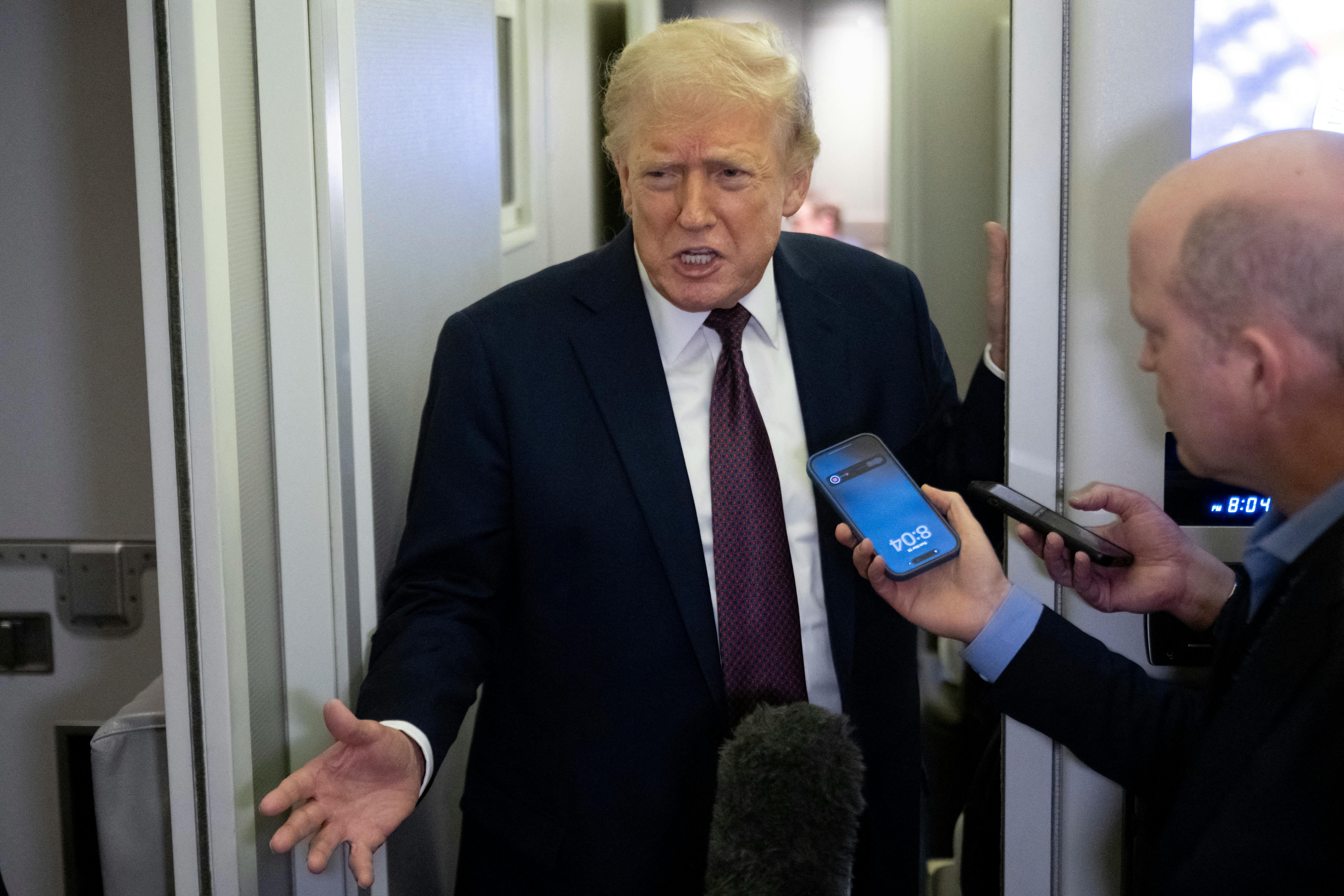 Donald Trump speaks to reporters aboard Air Force One