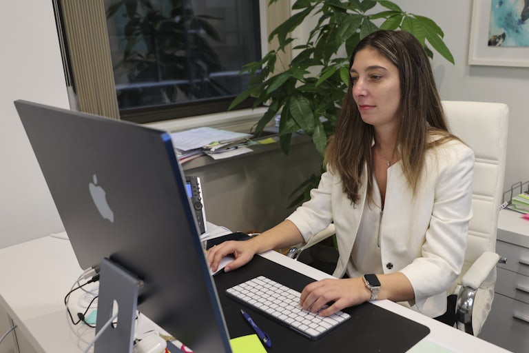 Immigration lawyer Nicole Micheroni sits at her desk in front of her computer in her office