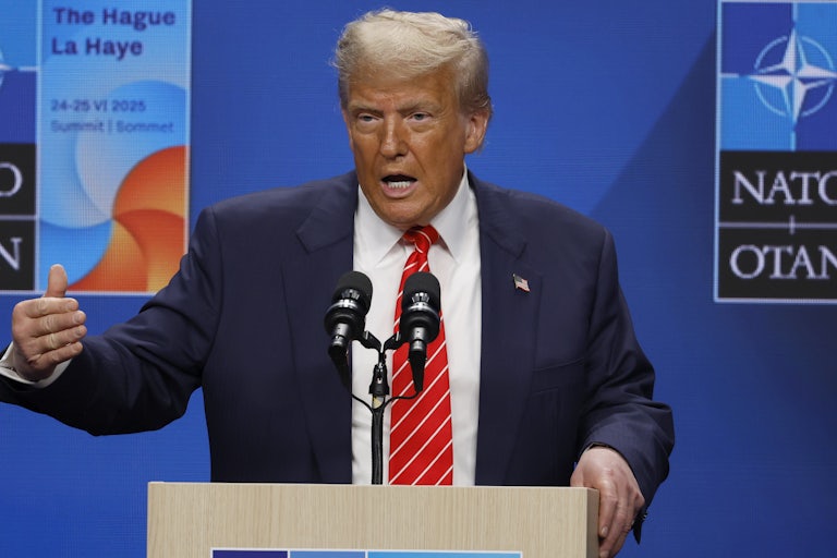 Donald Trump gestures while speaking at a podium during the NATO summit at The Hague