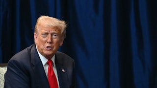 Donald Trump sits and speaks at an event