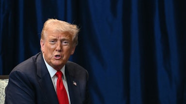 Donald Trump sits and speaks at an event
