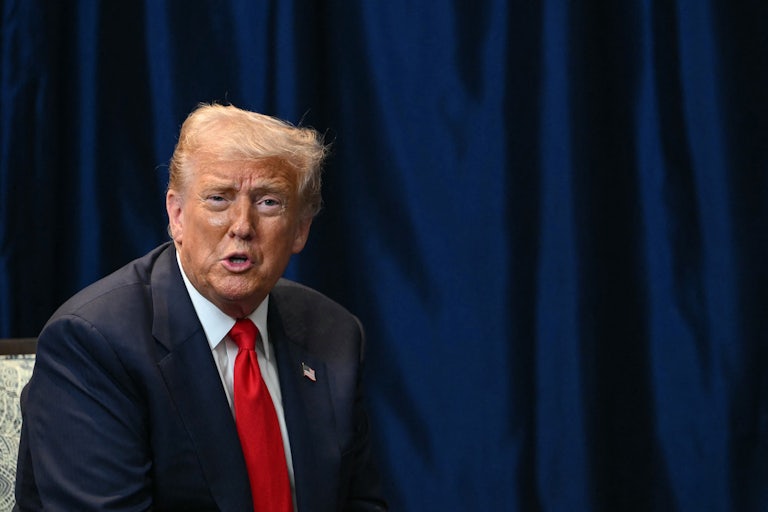 Donald Trump sits and speaks at an event