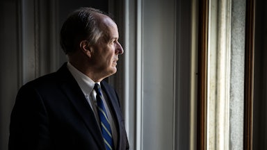 David Lebryk looks outside a window with his glasses in his hands