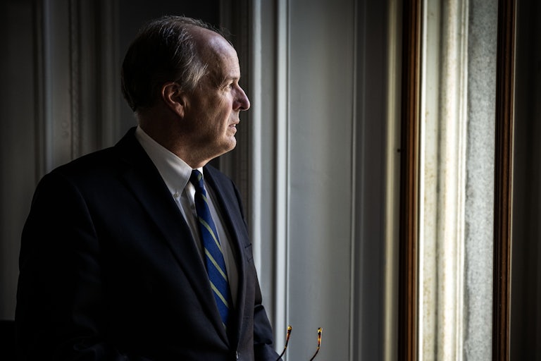 David Lebryk looks outside a window with his glasses in his hands
