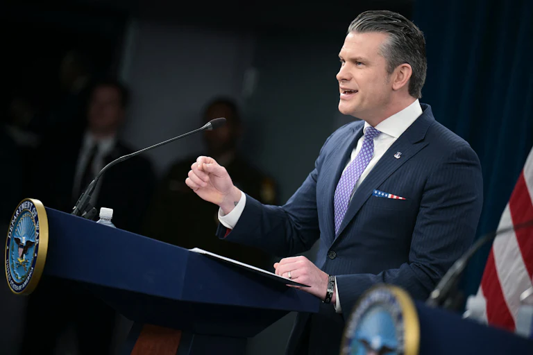 Defense Secretary Pete Hegseth gestures and speaks at a podium
