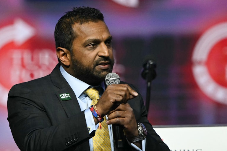 Kash Patel gestures while speaking into a microphone