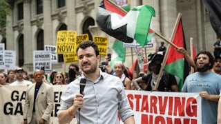 Mahmoud Khalil speaks as protesters gather behind him and wave the Palestinian flag.