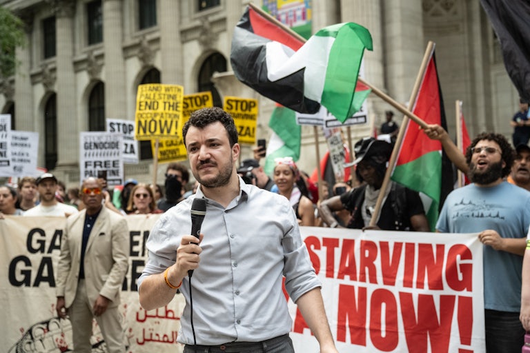 Mahmoud Khalil speaks as protesters gather behind him and wave the Palestinian flag.