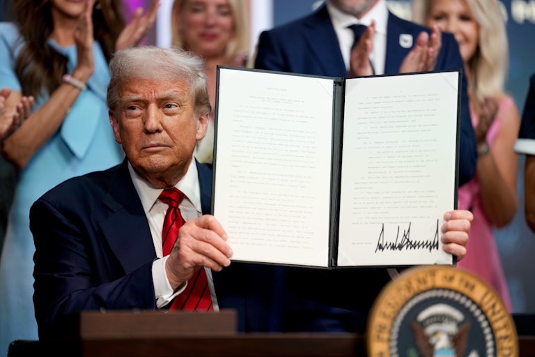 Donald Trump holds up a signed executive order.