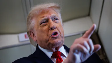 Donald Trump points while speaking to reporters on Air Force One