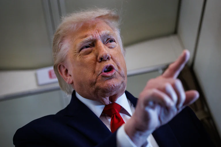 Donald Trump points while speaking to reporters on Air Force One