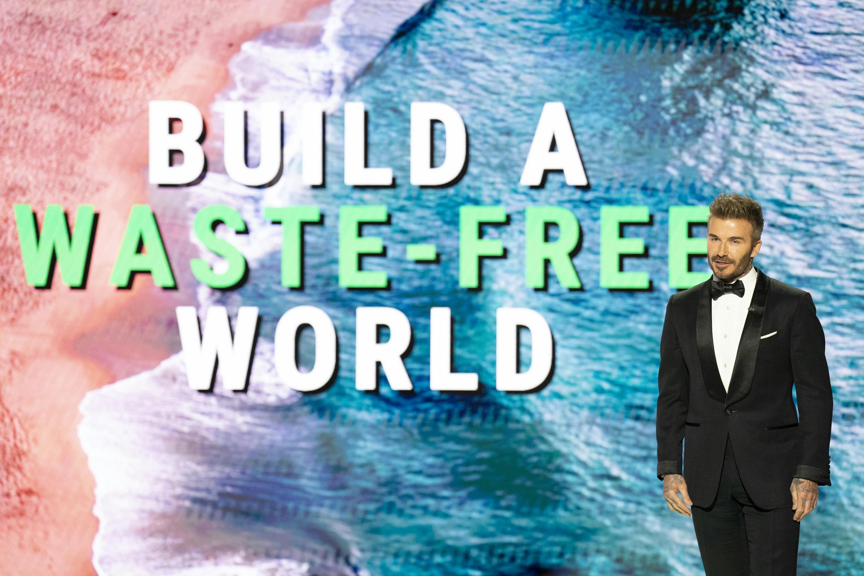 David Beckham stands in front of a screen reading Build a Waste-Free World. 
