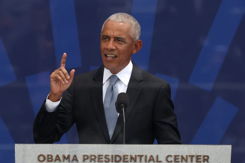 Barack Obama holds his right index finger in the air while speaking