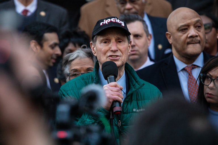 Ron Wyden speaks into a microphone during a protest against Elon Musk outside the Treasury Building in Washington, D.C.