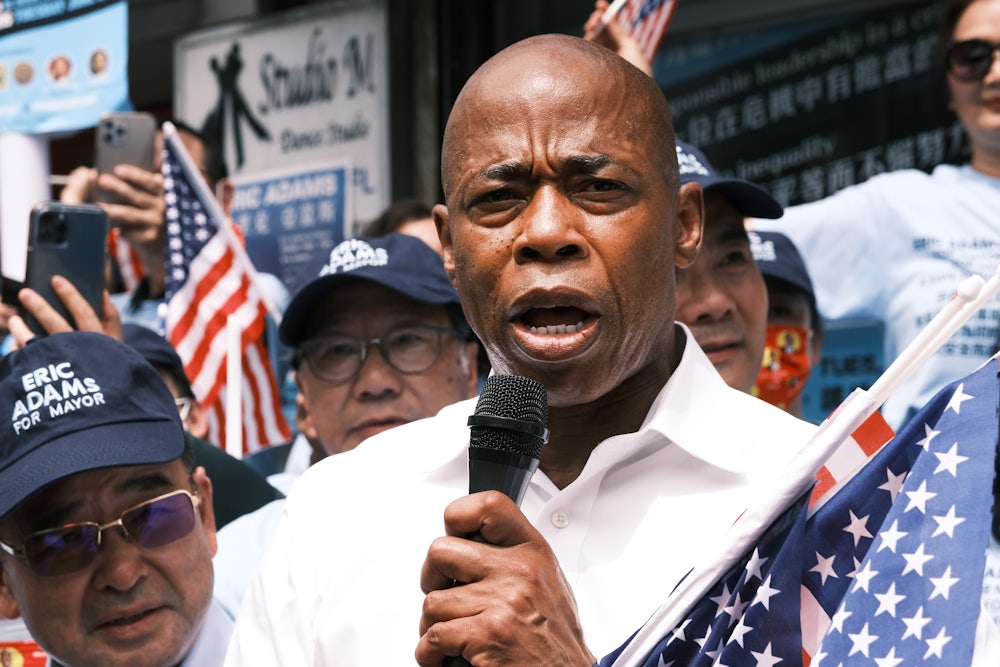 Democratic mayoral candidate Eric Adams holds a microphone as his supporters wave American flags.