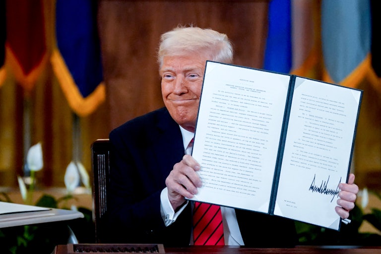 Donald Trump smiles and holds up a signed executive order to end the Department of Education