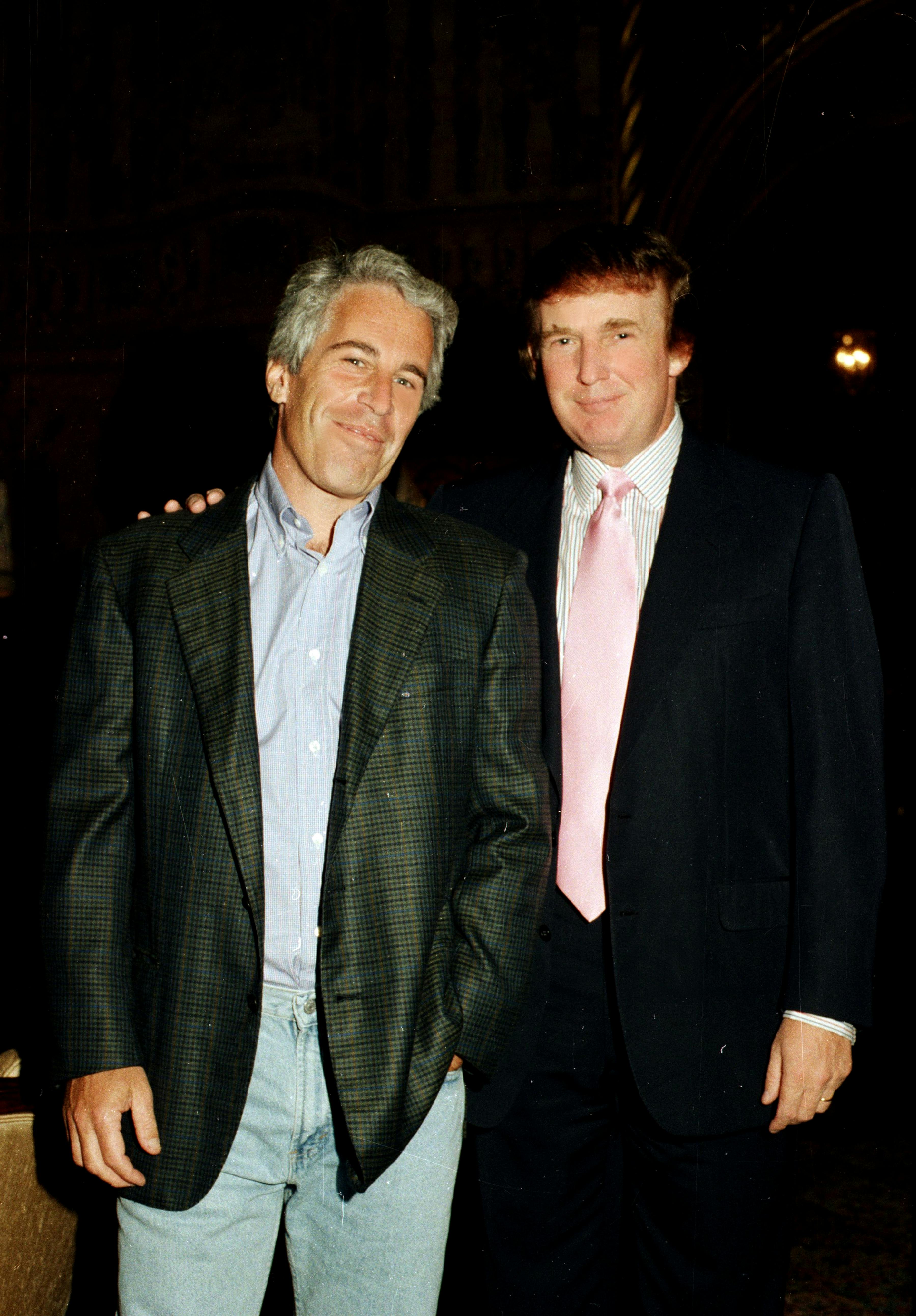 Jeffrey Epstein and Donald Trump smile for the camera while standing next to each other.