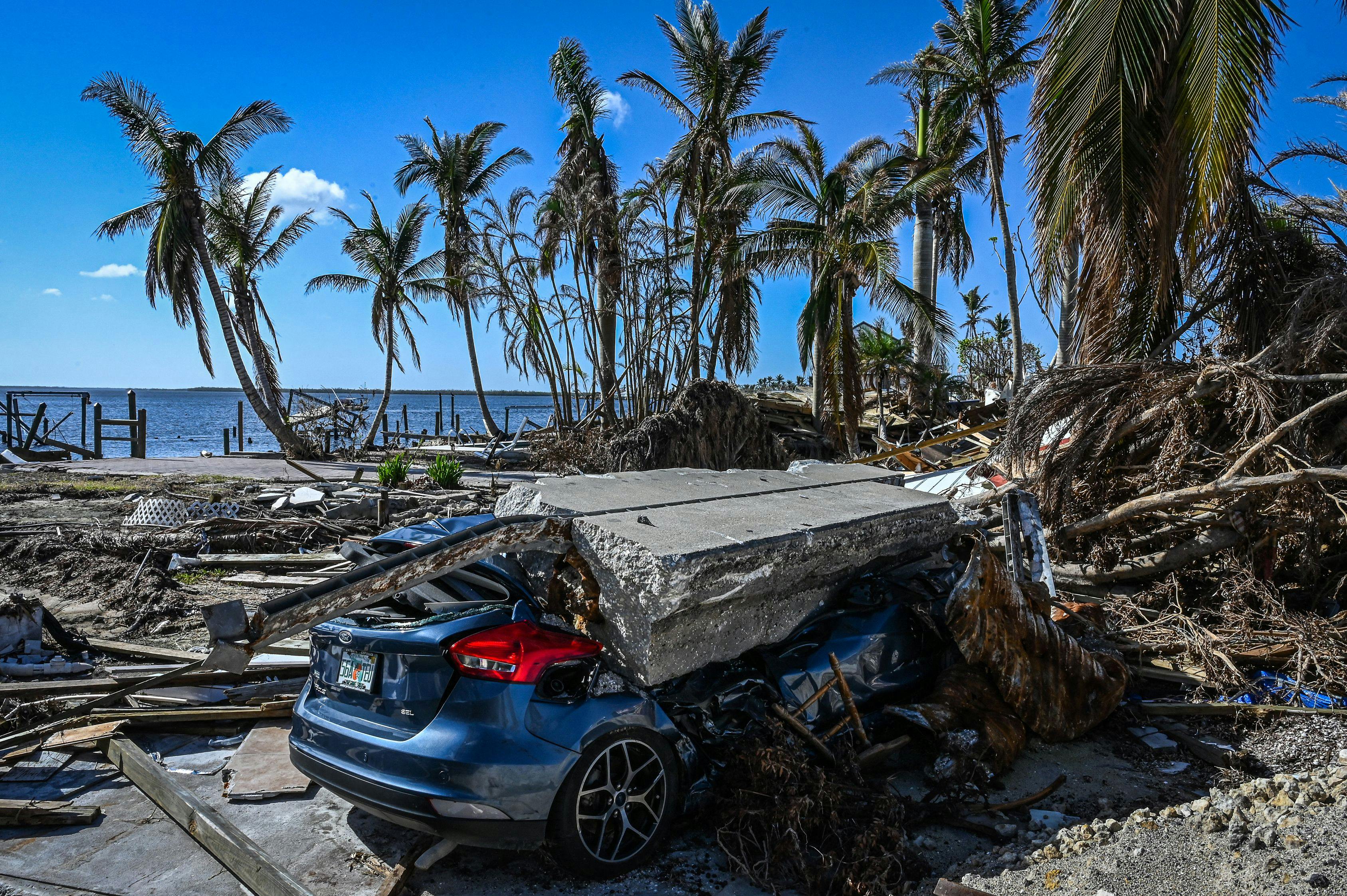 A piece of concrete lies on a crushed car amid wreckage from the hurricane.
