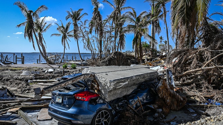 A piece of concrete lies on a crushed car amid wreckage from the hurricane.