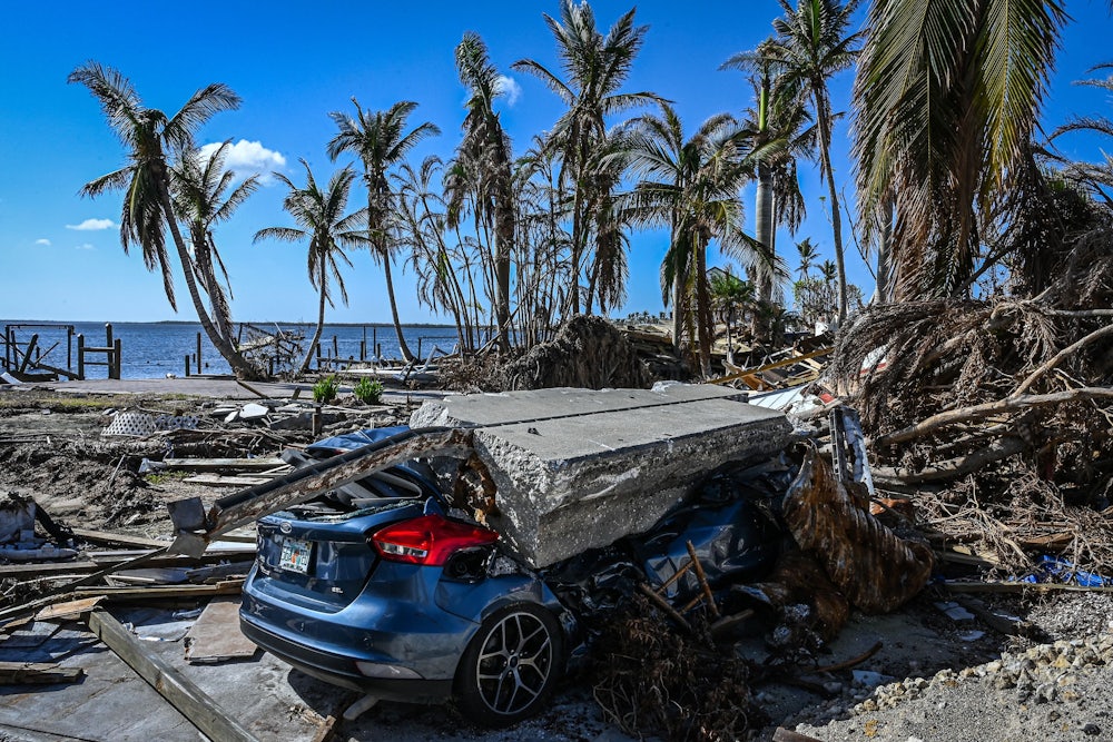 A piece of concrete lies on a crushed car amid wreckage from the hurricane.