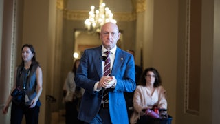 Senator Mark Kelly puts his hands together while walking in the Capitol