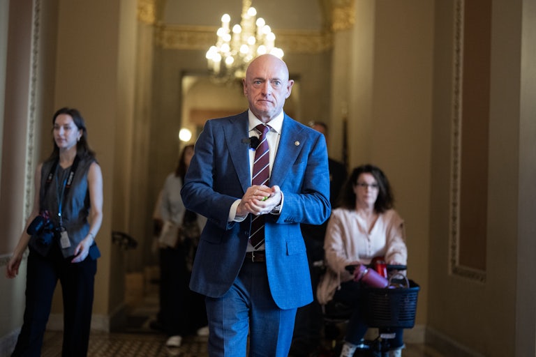 Senator Mark Kelly puts his hands together while walking in the Capitol