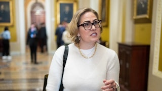 Kyrsten Sinema (with super dark, ugly drawn on eyebrows) in the Capitol.