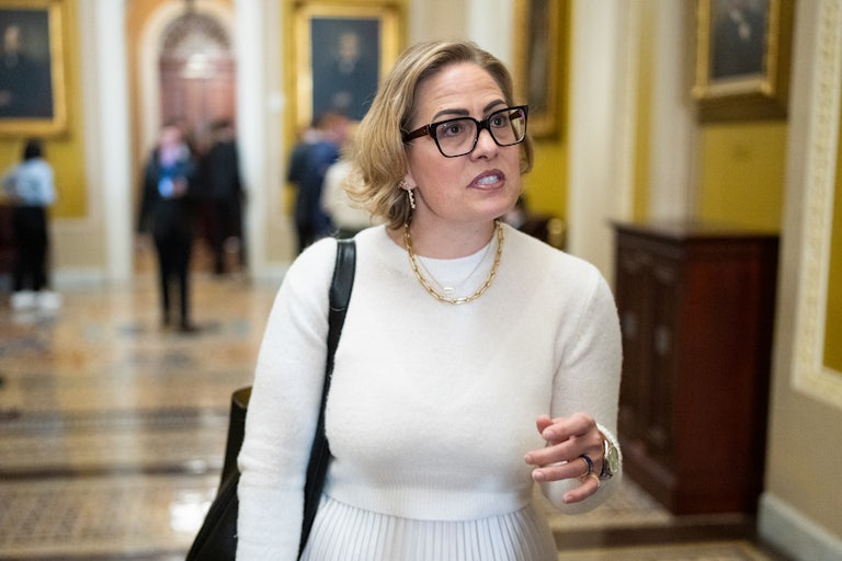 Kyrsten Sinema (with super dark, ugly drawn on eyebrows) in the Capitol.