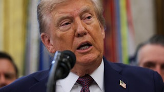 President Donald Trump speaks into a microphone.