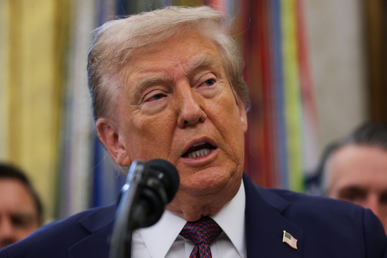 President Donald Trump speaks into a microphone.