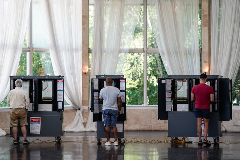 Three voters cast ballots at a polling site.