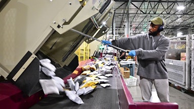 A postal worker sorts through mail and packages at the Los Angeles processing and distribution center. 