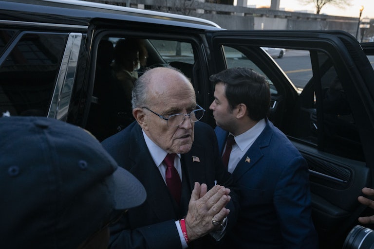 Rudy Giuliani exits a car and places his hands together as if in prayer
