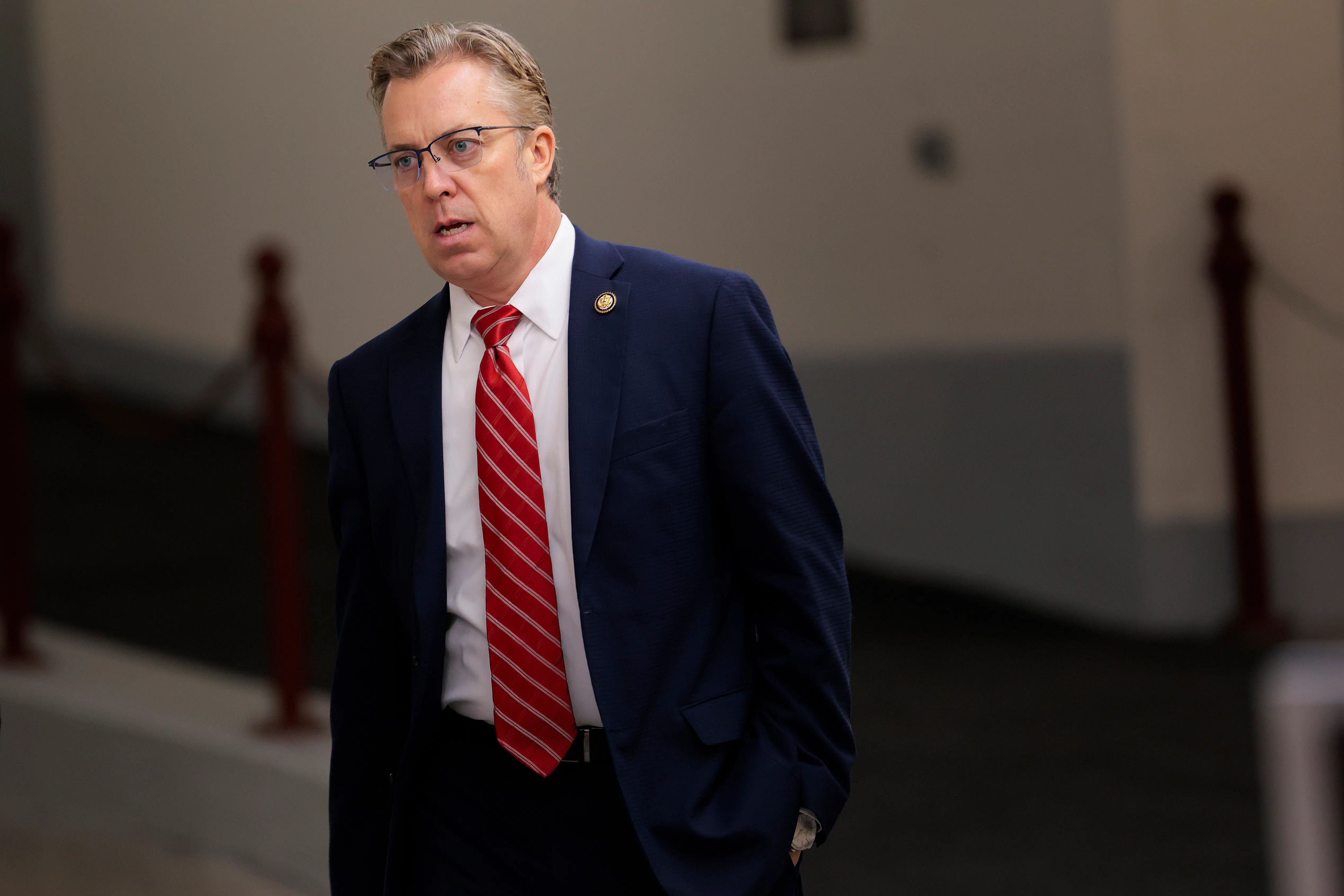 Representative Andy Ogles leans forward and opens his mouth slightly while walking in the Capitol