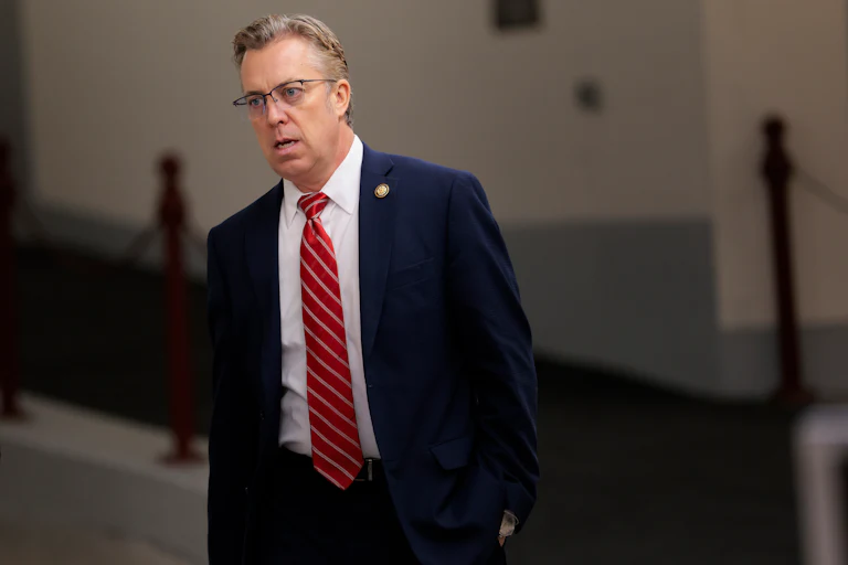 Representative Andy Ogles leans forward and opens his mouth slightly while walking in the Capitol