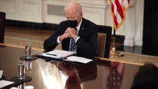 A masked Joe Biden looks down at his notes during a meeting with immigration policy advisors.