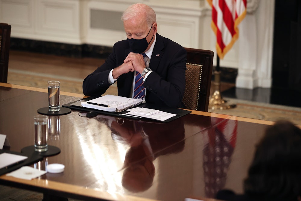 A masked Joe Biden looks down at his notes during a meeting with immigration policy advisors.