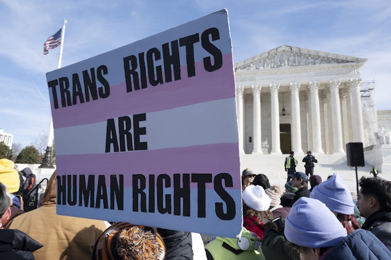 People protest in front of the Supreme Court. One large sign reads "Trans Rights Are Human Rights."