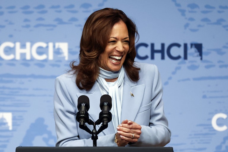 Kamala Harris smiles while standing at a podium